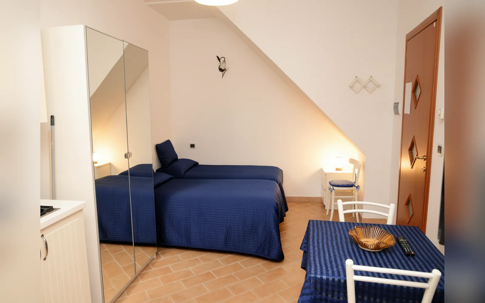 La Camera Magnolia con il letto blu, l’armadio a specchio e il tavolo apparecchiato